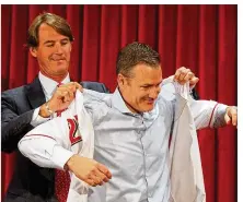  ?? DAVID JABLONSKI / STAFF ?? Dick Williams, the Reds’ president of baseball operations, helps new manager David Bell put on a Reds jersey Monday during a news conference at Great American Ball Park.