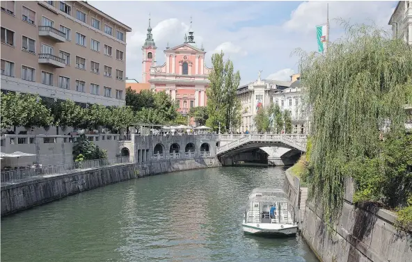  ?? — THE ASSOCIATED PRESS FILES ?? Tourists and residents walk across Tromostovj­e bridge in downtown Ljubljana, Slovenia. The tiny European nation is getting an outsized share of attention lately as the birthplace of Melania Trump, wife of U.S. president-elect Donald Trump.