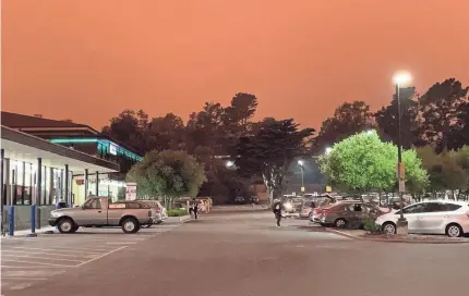  ?? ELIZABETH WEISE ?? A sky tinted orange by wildfires looms over the parking lot of a Safeway supermarke­t in San Francisco.