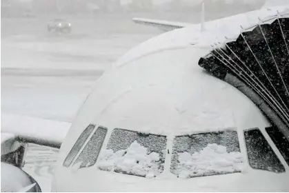  ?? ?? Snow covers a plane at John F Kennedy internatio­nal airport on Tuesday. Photograph: Frank Franklin II/AP