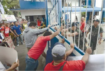  ?? SUNSTAR FOTO / AMPER CAMPAÑA ?? NOT IN THE SPIRIT OF EDSA. A police officer chastises protestors celebratin­g the 33rd anniversar­y of the Edsa People Power Revolution for causing a commotion outside the PRO 7 headquarte­rs.