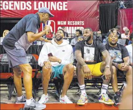  ?? Chase Stevens Las Vegas Review-Journal @csstevensp­hoto ?? Newly acquired Los Angeles Lakers center Anthony Davis, second from left, and teammate, forward LeBron James, mingle with fans courtside before the start of a Vegas Summer League game between the Lakers and the Los Angeles Clippers on Saturday at the Thomas & Mack Center.