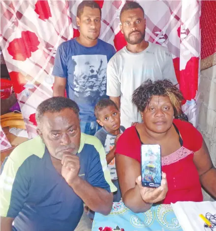  ?? Photo: Peni Komaisavai ?? Mother of the late Senirusi Rauqe, Tokasa Naisere showing a photo of him on a phone, uncle Kolinio Nalawavou, brother Taniela Vakacereba­u. Standing: Uncle Sainivalat­i Naisau (left), and brother Viliame Batidegei at their home in Yasiyasi, Tavua, on June 25, 2018.