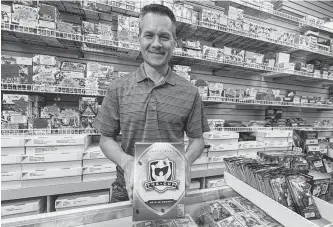  ?? POSTMEDIA ?? Wayne Wagner, owner of Wayne’s Sports Cards in west Edmonton, holds a pack of Upper Deck The Cup cards. An online auction for a Connor Mcdavid The Cup rookie card numbered 97 of 99 has a current bid of more than $70,000 US.