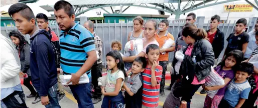  ?? AP ?? Immigrant families line up to enter the central bus station after they were processed and released by US Customs and Border Protection in McAllen, Texas. —