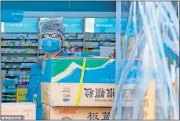  ?? [AREK RATAJ/ THE ASSOCIATED PRESS] ?? A clerk wearing a face mask and a plastic bag stands in a pharmacy in Wuhan in central China's Hubei Province, on Friday.