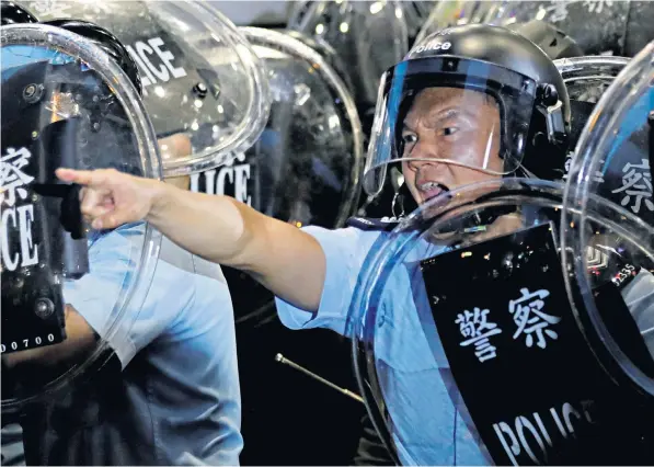  ??  ?? Police confront demonstrat­ors outside Mong Kok police station in Hong Kong yesterday. Below, Fu Guohao tied up by protesters after he was accused of being a spy sent to infiltrate their movement