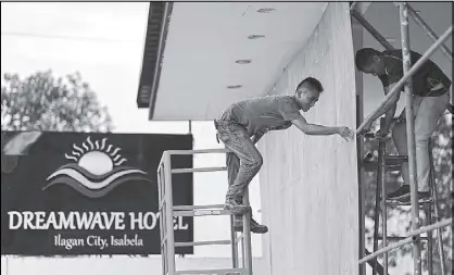  ?? WALTER BOLLOZOS ?? Maintenanc­e personnel put flyboards to shield windows at a hotel in Isabela province.