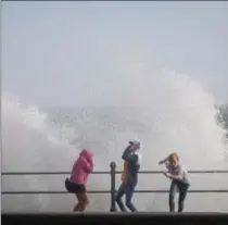  ?? MATT CARDY, GETTY IMAGES ?? People run from a wave whipped up by Hurricane Ophelia as it crashes over the seafront in Penzance in Cornwall, England.