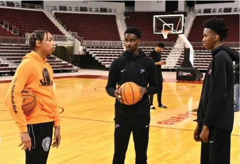  ?? (Pine Bluff Commercial/I.C. Murrell) ?? North Little Rock senior Nick Smith Jr. (from left), Little Rock Parkview senior Cameron Wallace and Parkview sophomore Dallas Thomas chat at a media event Wednesday ahead of the King Cotton Holiday Classic at Simmons Bank Arena in North Little Rock. In the background is North Little Rock senior Kel’el Ware, an Oregon signee. Smith signed with Arkansas, and Wallace signed with Central Arkansas.