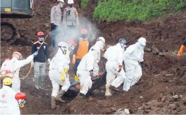  ?? — AFP ?? Rescuers are disinfecte­d as they remove the body of a landslide victim in Sumedang, West Java province, on Sunday.