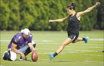  ?? Matt Rourke Associated Press ?? SOCCER STAR Carli Lloyd attempts a field goal as Baltimore punter Sam Koch holds the ball during a Ravens-Philadelph­ia Eagles joint practice. She converted several attempts, including one from 55 yards.