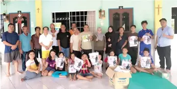  ??  ?? Zulhaidah (standing, sixth right) and her team join the longhouse villagers and their children in a group photo after handing over the school uniforms.