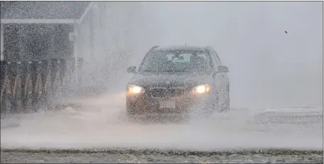  ?? MATT STONE — BOSTON HERALD ?? A car drives through ocean spray and snow during a nor’easter.
