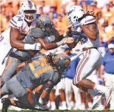  ?? STAFF PHOTO BY ROBIN RUDD ?? Florida’s Jordan Scarlett (25) breaks the tackle of Tennessee’s Jalen Reeves-Maybin (21) while Micah Abernathy is held by Florida’s Fred Johnson (74) in their 2016 game.