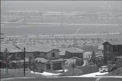  ?? DAVID MCNEW/GETTY IMAGES ?? A community housing project overlooks farms that are being rapidly converted into a vast suburb in San Bernardino County on July 11, 2007 near Rancho Cucamonga, California. A new study shows households in the state emit around 33% less carbon than any other state, though more affluent neighborho­ods emit more carbon dioxide than low income neighborho­ods.