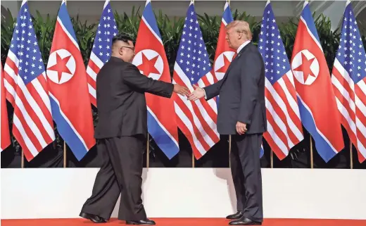  ??  ?? North Korean leader Kim Jong Un and U.S. President Donald Trump reach out to greet each other today in Singapore. EVAN VUCCI/AP