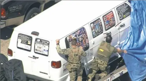  ?? WPLG-TV via AP ?? This frame grab from video provided by WPLG-TV shows FBI agents covering a van after the tarp fell off as it was transporte­d from Plantation, Fla., on Friday. Federal agents and police officers have been examining the van in connection with package bombs that were sent to high-profile critics of President Donald Trump. The van has several stickers on the windows, including American flags, decals with logos and text.