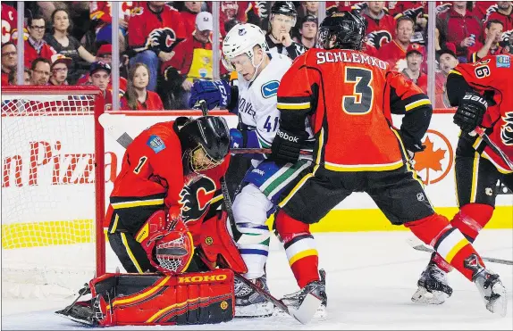  ?? — GETTY IMAGES FILES ?? Goalie Jonas Hiller of the Flames stops Ronalds Kenins, centre, of the Vancouver Canucks in Game 4 of the Western Conference quarterfin­als on April 21 at Scotiabank Saddledome in Calgary. Kenins signed a one-year deal with the Canucks on Monday.