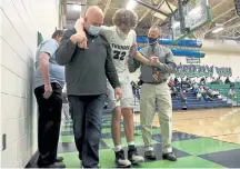  ??  ?? Zach Keller is helped off the court by his father, Jeff, left, and ThunderRid­ge athletic trainer, David Whitlockaf­ter he was injured on a play against Castle View.