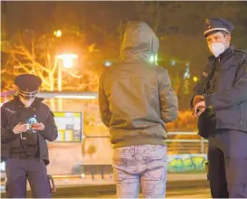  ??  ?? Police officers talk to a man during a curfew check at night in the Gorbitz district in Dresden, Germany.