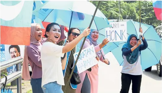  ??  ?? People power: With the support of a majority of Malaysians, Pakatan delivered a severe blow to Barisan in the recent election. Below: Sisters Nur Farahin Mohamed Yusoff, 25, and Nur Farhanah, 22, who are first-time voters, pose after casting their votes.