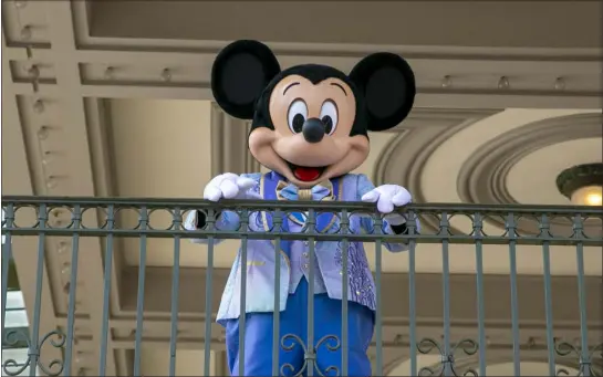  ?? TED SHAFFREY — THE ASSOCIATED PRESS FILE ?? An actor dressed as Mickey Mouse greets visitors at the entrance to Magic Kingdom Park at Walt Disney World Resort on April 18, 2022, in Lake Buena Vista, Fla. Winnie the Pooh and Mickey Mouse have recently entered the public domain, making it possible for artists to use them freely.