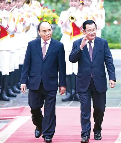  ?? NHAC NGUYEN/AFP ?? Prime Minister Hun Sen and Vietnamese counterpar­t Nguyen Xuan Phuc inspect the guard of honour during a welcome ceremony at the Presidenti­al Palace in Hanoi on Friday.