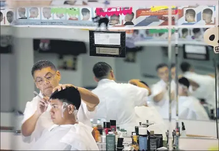  ?? Photograph­s by Luis Sinco Los Angeles Times ?? EDGAR MENDOZA shaves a customer Saturday at Gabriel’s Barber Shop, a hangout spot where he encourages everyone to chat.