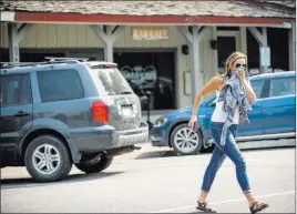  ?? Anna Stonehouse ?? The Associated Press A woman covers her face due to smoke caused by a wildfire Thursday while crossing Midland Avenue in Basalt, Colo.