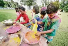  ?? ?? Elementary and middle school aged campers, covered with colored powder, refill their cups with powder during the Holi Festival celebratio­n at Hindu Heritage Youth Camp in 2019.