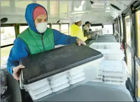  ?? SEAN D. ELLIOT/THE DAY ?? New London Public Schools food service staff members, from front to back, Denny Rivera, Julian Wilson, Samantha Wilson and Luis Martinez load a school bus Tuesday with food to be distribute­d to children around the city.