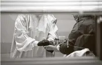  ?? Jeff Roberson / Associated Press ?? Registered nurse Chrissie Burkhiser hands medication to a COVID-19 patient inside an emergency room in Missouri.