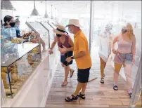  ??  ?? A plastic shield divides customers in line at Sift Bake Shop in Mystic.