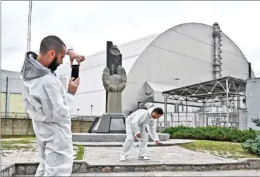  ?? AFP ?? Tourists take pictures at the New Safe Confinemen­t, a new metal dome encasing the destroyed reactor, at the Chernobyl plant in Ukraine on August 15.