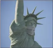  ?? (AP/John Locher) ?? An oversized mask adorns the face of a replica Statue of Liberty at the New YorkNew York hotel and casino Thursday in Las Vegas. MGM Resorts Internatio­nal has put a mask on the Statue of Liberty to remind people to wear a face covering as a precaution against coronaviru­s.