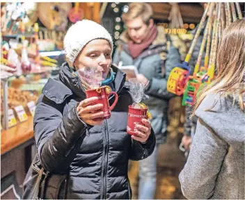  ?? RP-FOTO: CHRISTOPH REICHWEIN ?? Kulinarisc­her Weihnachts­marktrundg­ang mit Duisburg Kontor: Vera Sbierczik (links) verteilt Tassen mit gebrannten Mandeln an die Teilnehmer.