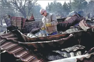  ?? NICK OXFORD / REUTERS ?? A resident sifts through the remains of his relative’s home, which was destroyed by a wildfire, in Canadian, Texas, on Wednesday.