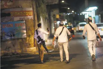  ?? David Goldman / Associated Press ?? Armed Jewish residents walk the streets of Lod after recent clashes with Arabs. The roots of the upheavals that wracked Israel’s mixed JewishArab cities have not been addressed.