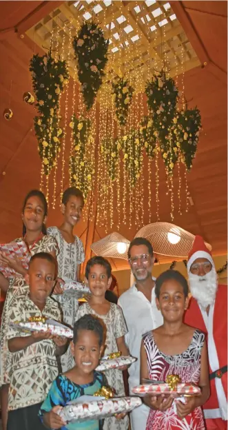  ?? Waisea Nasokia ?? Multi Property Vice President and Sheraton Resorts Fiji Complex general manager Neeraj Chadha (third from right) with Santa Claus David Senileba and children with their gifts during the Christmas tree lighting which hangs on the ceiling. Photo: