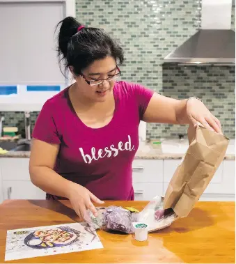  ?? THE CANADIAN PRESS ?? Jayne Zhou unwraps a HelloFresh Cajun fish tacos meal kit in her Vancouver home.