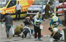  ?? OREN ZIV/AP ?? Israeli soldiers and members of the Zaka paramedic service clean blood from the site of a deadly attack Tuesday near the West Bank Jewish settlement of Ariel.