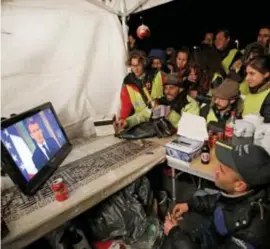  ?? FOTO REUTERS ?? Gele hesjes volgen de toespraak van president Macron. Of zijn tegemoetko­mingen voldoende zijn, is maar zeer de vraag.