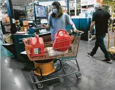  ??  ?? Gigi Hlavink purchases gas cans and other items at a Home Depot store. Supplies to weather the storm, protect homes and get ready for power outages were flying off the shelves.