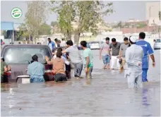  ??  ?? متطوعون يدفعون سيارة متضررة من وسط مياه األمطار بجدة أخيرا. (تصوير: ناصر محسن)