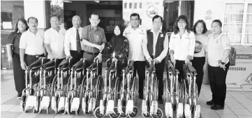  ??  ?? Lee (fifth left) hands over the wheelchair­s to Dr Hartini.