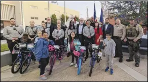 ?? JULIE DRAKE/VALLEY PRESS ?? Children Alexya Lewis (center left), Payton Yarbrough (center) and Felipe Medina (center right) show off the bicycles they received Tuesday at the City of Lancaster’s annual Christmas tree lighting ceremony and Antelope Valley Sheriff’s Boosters Children’s Bike Giveaway.