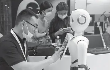  ?? WANG ZHUANGFEI / CHINA DAILY ?? An exhibitor calibrates a robot before the opening of the World Robot Conference.