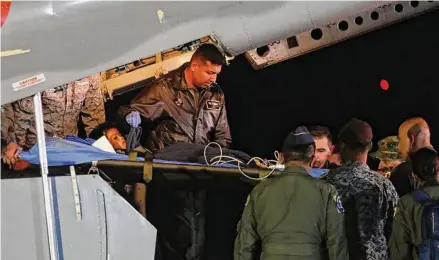  ?? John Vizcaino/Associated Press ?? Colombian military personnel on Saturday unload one of four Indigenous children who survived 40 days after a plane crash. The children braved the jungle for 40 days before being found alive by Colombian soldiers.