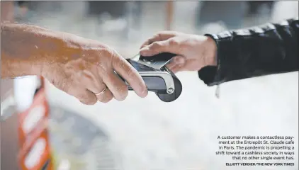  ?? ELLIOTT VERDIER/THE NEW YORK TIMES ?? A customer makes a contactles­s payment at the Entrepôt St. Claude cafe in Paris. The pandemic is propelling a shift toward a cashless society in ways
that no other single event has.